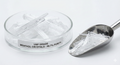 Menthol crystals in a glass dish with a metal scoop on a white background